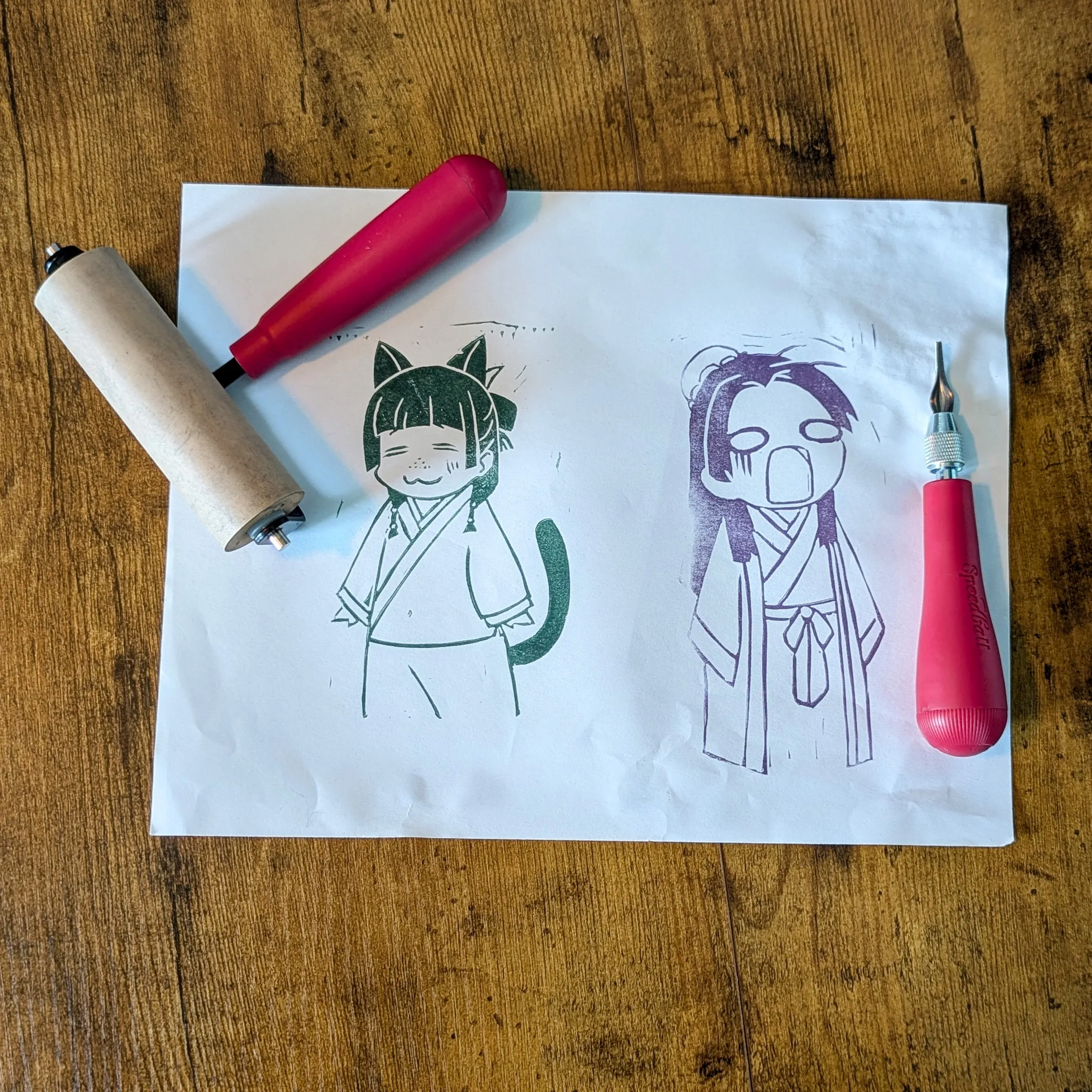 an image of the progress on creating linocut prints of maomao and jinshi from apothecary diaries. includes carving and printing tools